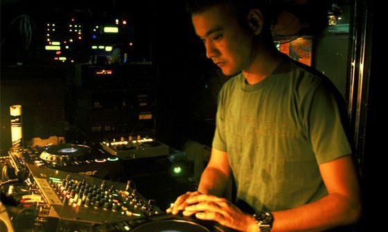 Satoshi Tomiie playing in front of a mixer and cd players