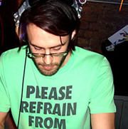Will Saul with headphones on his head mixing music in a club.