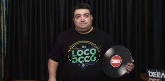 DJ Loco oCco in spatele pupitrului cu playere de la Radio DEEA cu un disc pe care se poate citi radio deea in mana stanga - partea dreapta a fotografiei
